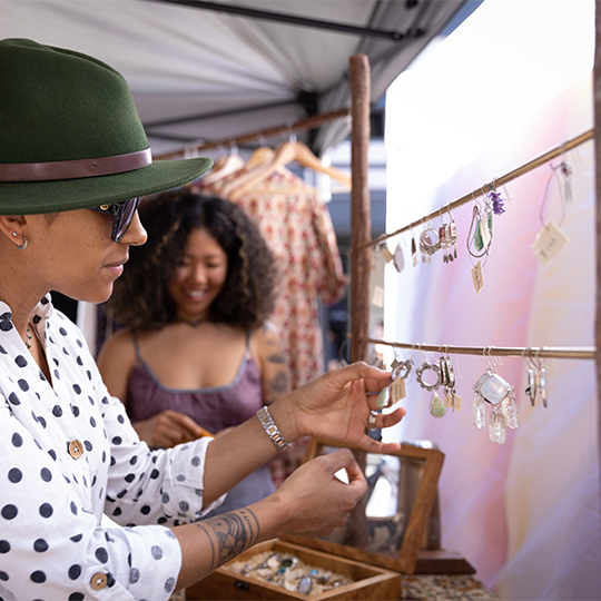 a woman looking at earrings on a stand